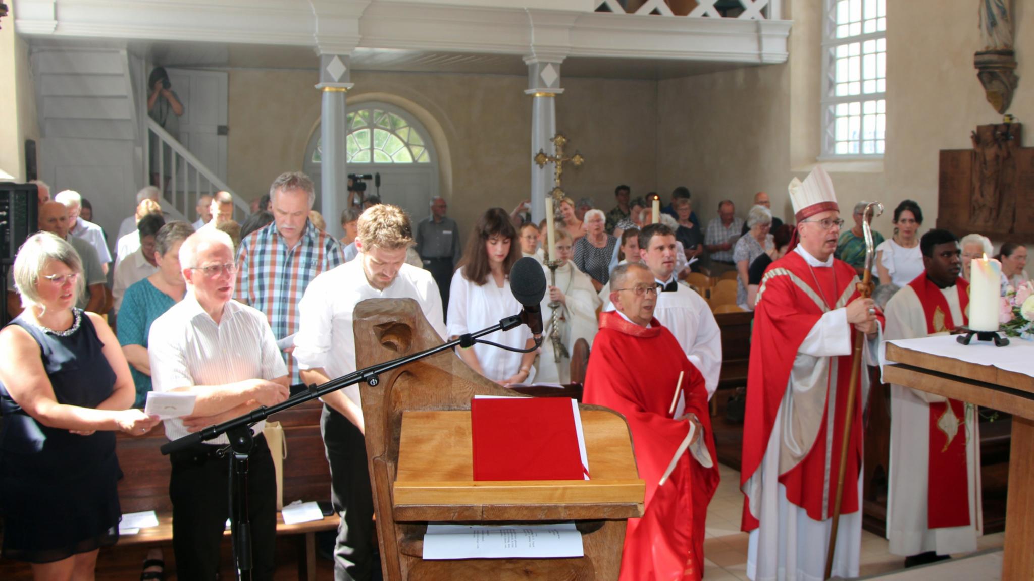 Blick vom Altarraum in eine Kirche, in der Menschen stehen.