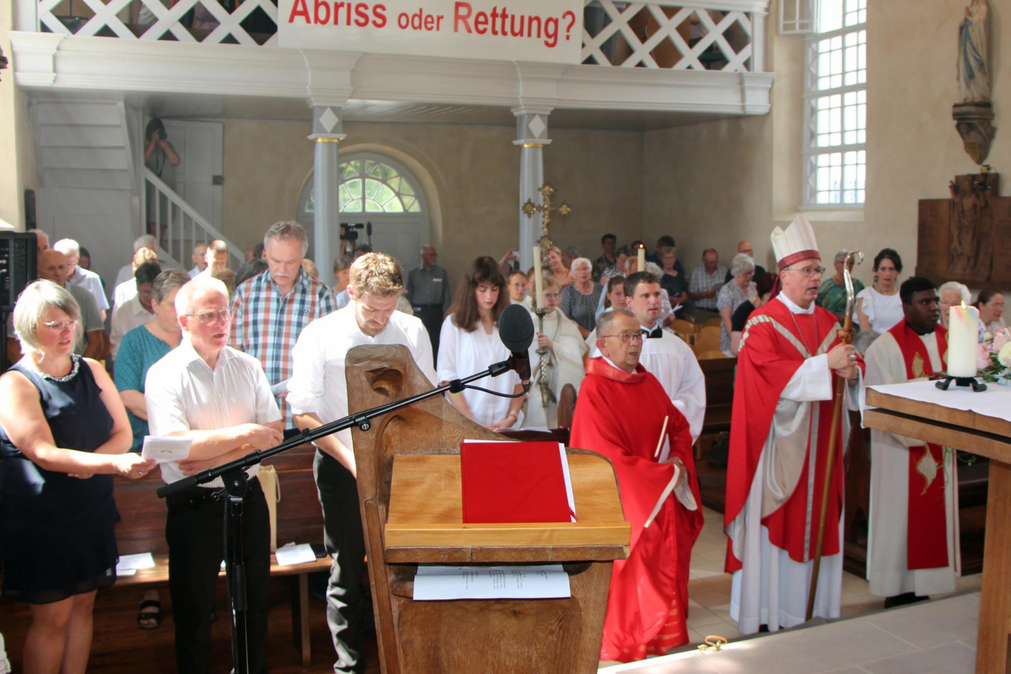 Blick vom Altarraum in eine Kirche, in der Menschen stehen.