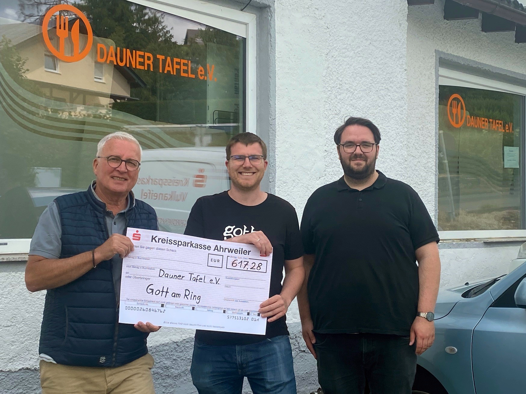 Christian Bauer (links) und Jörg Freitag (rechts) freuen sich über die Spende, die Philipp Hein vom Gott-am-Ring-Zelt der Dauner Tafel überreicht.